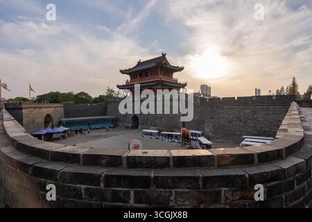 Die alte Stadtmauer von Jingzhou China überragt den Innenhof mit Fahrzeugen und Fahnen. Stockfoto