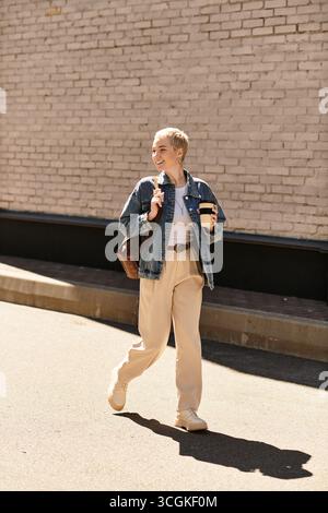 Glückliche junge Frau geht draußen, trinkt Kaffee und genießt ihre Umgebung. Stockfoto