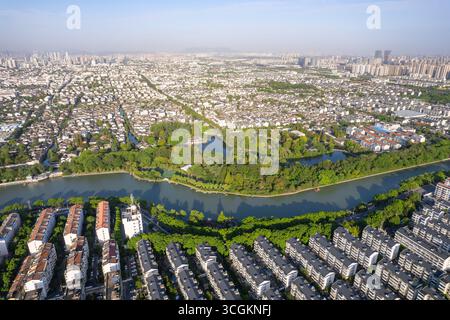 Die chinesische Stadtlandschaft von Hangzhou zeigt sich in gewundenen Flüssen und grünen Parks mit Gebäuden. Stockfoto