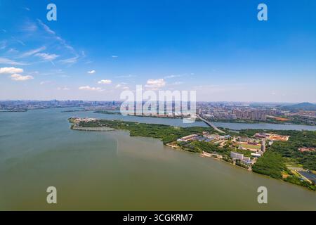 Panoramablick aus der Vogelperspektive des Jiangxia District in Wuhan, China, mit ruhigem Wasser, städtischer Entwicklung und üppigen Inseln. Stockfoto