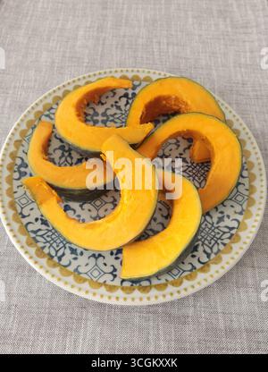 Stücke, Kürbisscheiben auf Porzellanplatte mit blauem Muster. Landwirtschaftliche Produkte und gesunde Ernährung. Küche und Hausmannskost. Stockfoto