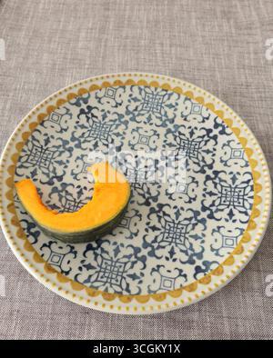 Stücke, Kürbisscheiben auf Porzellanplatte mit blauem Muster. Landwirtschaftliche Produkte und gesunde Ernährung. Küche und Hausmannskost. Stockfoto