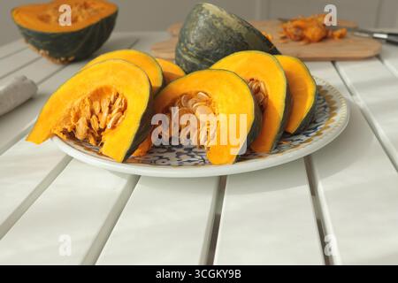 Stücke, Kürbisscheiben auf Porzellanplatte mit blauem Muster. Landwirtschaftliche Produkte und gesunde Ernährung. Küche und Hausmannskost. Stockfoto
