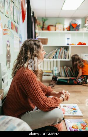 Lehrer, der Schüler beim Spielen im montessori-Vorschulzimmer beobachtet Stockfoto