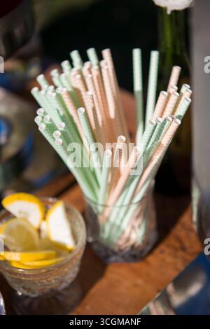 Papierhalme mit pastellfarbenen Streifen in Glas an der Drink Station Stockfoto