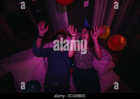 Zwei Freunde feiern zu Hause eine Geburtstagsparty mit farbenfrohen Dekorationen Stockfoto