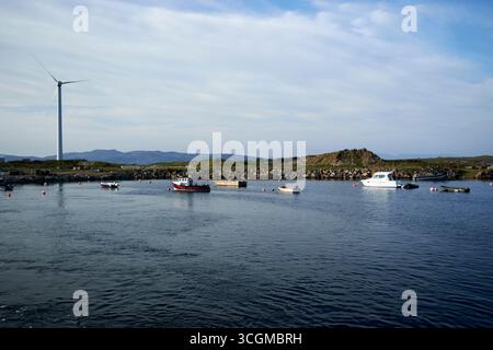 Windkraftanlage und kleine Fischerei- und Freizeitboote vor Anker im Hafen des Burtonport County donegal republik irland Stockfoto