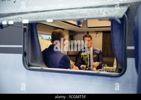 Düsseldorf, Deutschland. August 2025. Hendrik Wüst, Ministerpräsident Nordrhein-Westfalens (CDU), sitzt während eines Rundgangs durch den "Caravan Salon - Fachmesse für Caravaning, Camping und Outdoor-Tourismus" in einem Wohnwagen. Bis Zum 7 . Im September werden mehr als 810 Aussteller in 15 Messehallen und auf dem Freigelände die Produkte und Dienstleistungen der Branche präsentieren. Quelle: Henning Kaiser/dpa/Alamy Live News Stockfoto