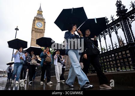 Touristen schützen sich vor dem Regen unter Regenschirmen, während sie Big Ben in Westminster, Zentrum von London, besuchen. Bilddatum: Freitag, 29. August 2025. Stockfoto