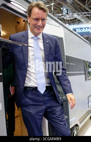 Düsseldorf, Deutschland. August 2025. Hendrik Wüst, Ministerpräsident von Nordrhein-Westfalen (CDU), kommt während eines Rundgangs durch den "Caravan Salon - Messe für Caravaning, Camping und Outdoor-Tourismus" aus einem Wohnwagen. Bis Zum 7 . Im September werden mehr als 810 Aussteller in 15 Messehallen und auf dem Freigelände die Produkte und Dienstleistungen der Branche präsentieren. Quelle: Henning Kaiser/dpa/Alamy Live News Stockfoto