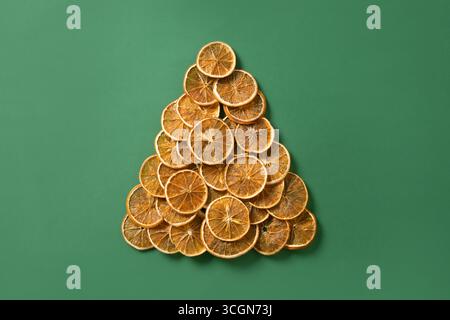 Umweltfreundlicher alternativer Weihnachtsbaum aus natürlichen getrockneten Orangenscheiben auf grünem Hintergrund. Essen vegan. Frohes Neues Jahr. Blick von oben. Weihnachten gre Stockfoto