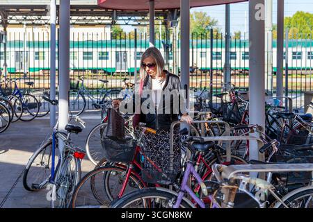 Eine Frau mit grauem Haar und Sonnenbrille steht mitten auf einem Fahrradparkplatz Stockfoto