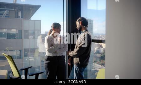 Geschäftskollegen, die sich über das Bürofenster unterhalten Stockfoto
