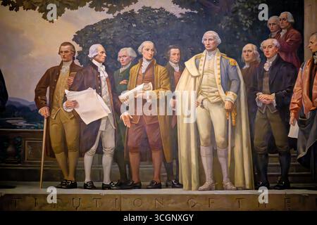 Barry Faulkner's The Constitution Mural Detail in National Archives in Washington DC // WASHINGTON DC – Ein Detail aus Barry Faulkners monumentalem Wandbild „The Constitution of the United States“ zeigt George Washington in einem weißen cape, das die Verfassung von James Madison in einer allegorischen Präsentationsszene erhält. Das 1936 fertiggestellte, 14 Meter x 37 Meter große Ölgemälde auf Leinwand zeigt die friedliche Gestaltung des amerikanischen Verfassungsrahmens durch hellere, harmonische Farben und klaren blauen Himmel, die im Kontrast zu den dunkleren Tönen des begleitenden Wandgemäldes zur Unabhängigkeitserklärung stehen. Faulkne Stockfoto