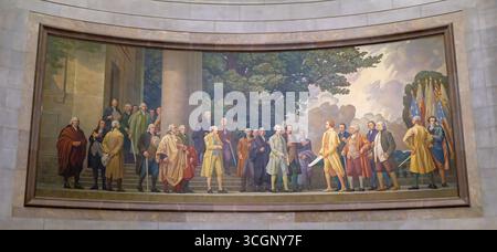 Barry Faulkner’s Declaration of Independence Mural in National Archives Rotunda in Washington DC // WASHINGTON DC – Barry Faulkners Deklaration der Unabhängigkeit zeigt Thomas Jefferson, der John Hancock das Gründungsdokument in einer allegorischen Szene präsentiert, die zwischen 1935-1936 für die Rotunde des National Archives Building geschaffen wurde. Das 14 Fuß x 37 Fuß große Öl-auf-Leinwand-Werk stellt eine von zwei monumentalen Wandgemälden dar, die im Rahmen des Bundeskunstprogramms der New Deal-Ära für 42.000 US-Dollar in Auftrag gegeben wurden. Faulkner nahm symbolische Elemente mit, darunter Sturmwolken, die den bevorstehenden Unabhängigkeitskrieg repräsentieren Stockfoto