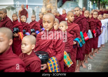 Mandalay Myanmar // MANDALAY, Myanmar — buddhistische Novizen stehen zum Mittagessen im Mahagandayon Kloster an, einer der größten Klosteruniversitäten in Myanmar. Bei diesem täglichen Ritual nehmen Tausende Mönche und Novizen an einer stillen Almosenprozession vor dem Hauptmahl teil. Das Kloster befindet sich in Amarapura, einer ehemaligen königlichen Hauptstadt in der Nähe von Mandalay, und ist ein bedeutendes Zentrum für klösterliche Bildung und das Studium des Theravada-Buddhismus. Es beherbergt Tausende von Mönchen und Novizen, die ihnen eine religiöse Ausbildung und tägliche Nahrung bieten. Die monas Stockfoto
