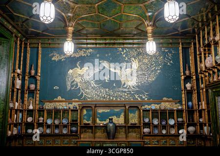 Peacock Room Smithsonian National Museum of Asian Art Washington DC // WASHINGTON DC — The Peacock Room, oder Harmony in Blue and Gold: The Peacock Room, ist ein Meisterwerk ästhetischer Innenarchitektur des US-amerikanischen Künstlers James McNeill Whistler. Dieser opulente Raum mit einem markanten goldenen Pfauengemälde vor blau-grünem Hintergrund befindet sich in der Freer Gallery of Art, Teil des Smithsonian National Museum of Asian Art Ursprünglich zwischen 1876 und 1877 für das Londoner Haus des Reedermagnaten Frederick Leyland geschaffen, diente es als Speisesaal, um seine Sammlung von chinesischem Blau-A zu präsentieren Stockfoto