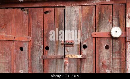 Scheunenplanke Türen mit einem Riegel, verstörte Plankenoberfläche und rostende Metallbefestigungen, Scheunenstrukturhintergrund, geschlossene Türen mit schöner Textur Stockfoto