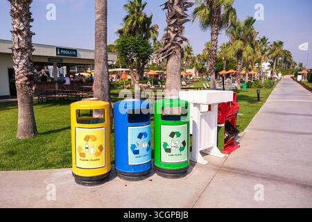 belek, Turkiye, 27.07.2025 farbenfrohe Recyclingbehälter auf grünem Gras in der Nähe einer Poolbar in einem Resort, die sich auf Umweltverantwortung während des Urlaubs konzentrieren Stockfoto