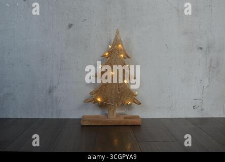 Nahaufnahme eines kleinen Weihnachtsbaums aus Holz, verziert mit leuchtenden Lichtern. Stockfoto