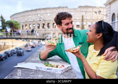 Glückliches Paar, das Pizza vor dem kolosseum in Rom isst. Stockfoto