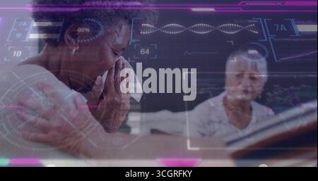 Eine ältere Frau, die ein Tuch am Heimtisch hält, mit Laptop, der Gesundheitsdaten anzeigt, Kopierraum Stockfoto