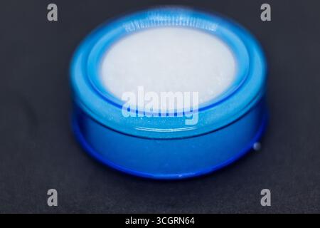 Runder blauer WasserPod, der in Geldzählmaschinen auf dunklem Tischplattenhintergrund verwendet wird. Stockfoto