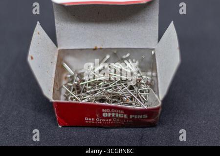 Rustikale Büro-Pins-Box mit silbernen Nägeln auf dunklem Stoffhintergrund Stockfoto