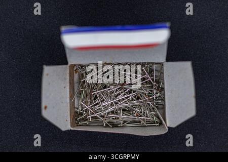 Gebrauchte silberne Daumentaster in Red Box auf strukturiertem dunklem Hintergrund Stockfoto