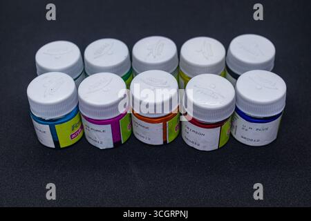 Lebendige Acrylfarben-Gläser in verschiedenen Farben auf dunklem Hintergrund Stockfoto