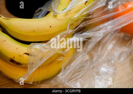 Ein Haufen reifer Bananen, in Plastik gewickelt, auf einem Holztisch. Ideal für gesunde Ernährung, frische Produkte oder Lebensmitteleinkäufe. Stockfoto