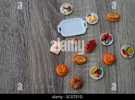 Eine köstliche Sammlung von Miniatur-Lebensmitteln auf einem Holztisch Frühstücks-Gebäck-Brötchen Stockfoto