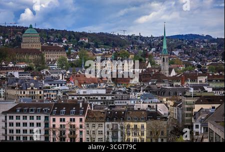 Ein Blick aus der Vogelperspektive auf die Skyline der Stadt mit ihren historischen Gebäuden, markanten Kirchtürmen und bewaldeten Hügeln unter bewölktem Himmel in Zürich, Schweiz Stockfoto