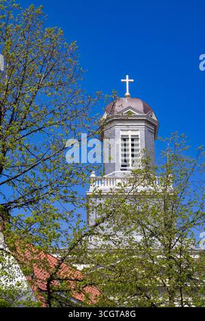 Leiden, Niederlande, 25.04.2025Eer Kirchturm in Leiden, Niederlande, erhebt sich mit einem Kuppeldach und goldenem Kreuz darüber, eingerahmt von grünen Frühlingsbäumen Stockfoto