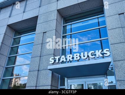 Warschau, Polen. August 2025. Eintritt zu einem Starbucks Coffee Shop in einem modernen Glas- und Betongebäude Stockfoto