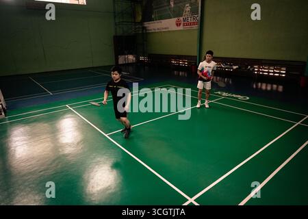 Zwei Spieler, die in einem Badmintonspiel auf einem Hallenplatz antreten Stockfoto