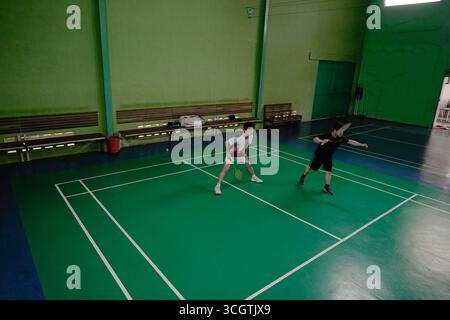 Zwei Spieler, die in einem Badmintonspiel auf einem Hallenplatz antreten Stockfoto