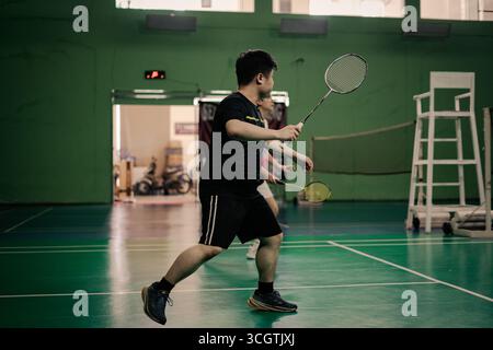 Zwei Spieler, die in einem Badmintonspiel auf einem Hallenplatz antreten Stockfoto