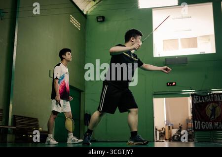 Zwei Spieler, die in einem Badmintonspiel auf einem Hallenplatz antreten Stockfoto