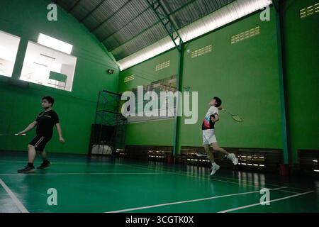 Zwei Spieler, die in einem Badmintonspiel auf einem Hallenplatz antreten Stockfoto