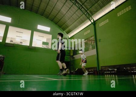 Zwei Spieler, die in einem Badmintonspiel auf einem Hallenplatz antreten Stockfoto