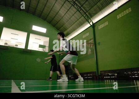 Zwei Spieler, die in einem Badmintonspiel auf einem Hallenplatz antreten Stockfoto