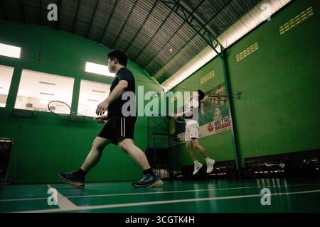 Zwei Spieler, die in einem Badmintonspiel auf einem Hallenplatz antreten Stockfoto