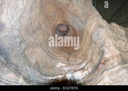 Ein großer Felsen mit einem Loch in der Mitte. Das Loch ist von einer weißen Substanz umgeben. Der Felsen scheint alt und verwittert zu sein Stockfoto