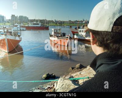 Touristen genießen den Blick auf die bunten Fischerboote, die an einem sonnigen Tag im Hafen vertäut sind Stockfoto
