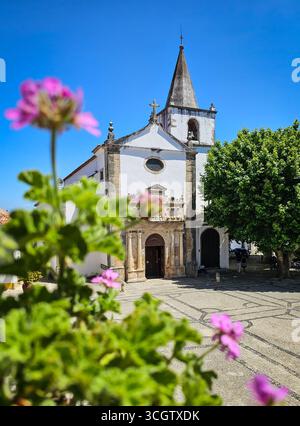 Igreja de Santa Maria mit Blumen im Vordergrund in Óbidos, Portugal Stockfoto