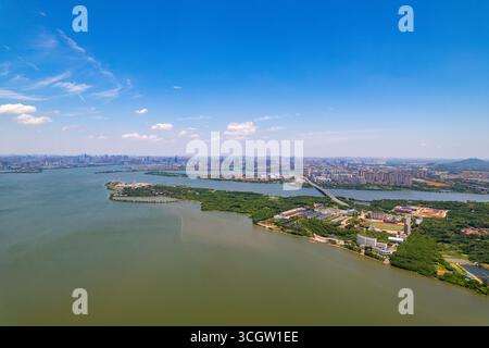 Panoramablick aus der Vogelperspektive des Jiangxia District in Wuhan, China, mit ruhigem Wasser, städtischer Entwicklung und üppigen Inseln. Stockfoto