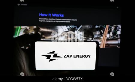 In dieser Abbildung hält eine Person ein Mobiltelefon mit dem Logo des US-amerikanischen Fusionsenergieunternehmens Zap Energy Inc. Auf dem Bildschirm vor der Webseite. Stockfoto