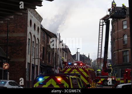 Rettungsdienst-Szene mit Feuerwehrleuten, Feuerwehrfahrzeugen und Luftplattform, die bei einem Brand in einem Stadtgebäude anwesend sind Stockfoto