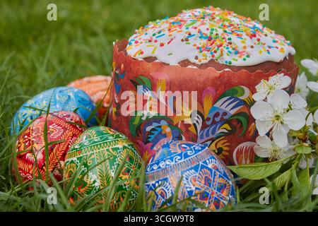 Osterhintergrund auf Gras mit Osterkuchen im Korb und ostereiern Stockfoto